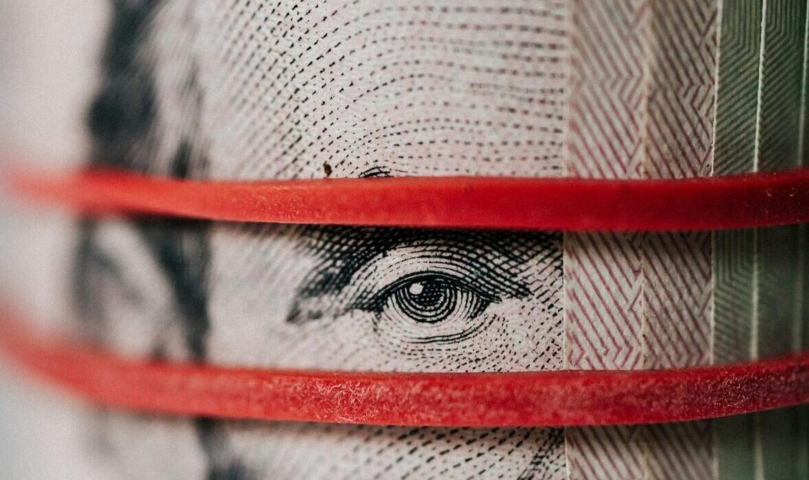 Closeup of rolled United States five dollar bills tightened with red rubber band